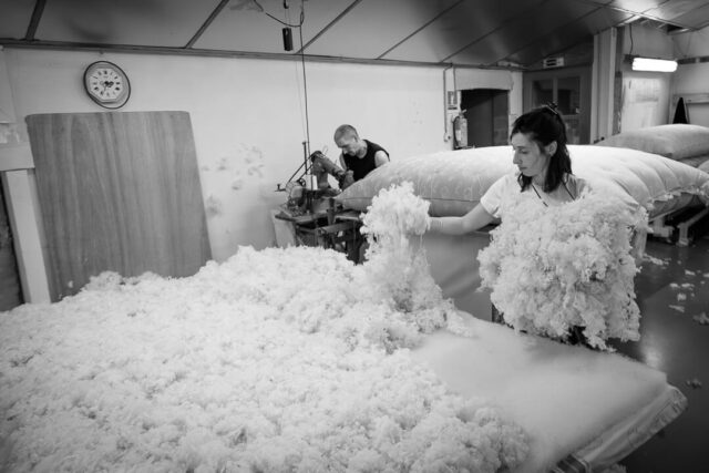 Matelassière bâtissant un matelas en laine à Saint-Pierreville, étalant les flocons sur un tissu.