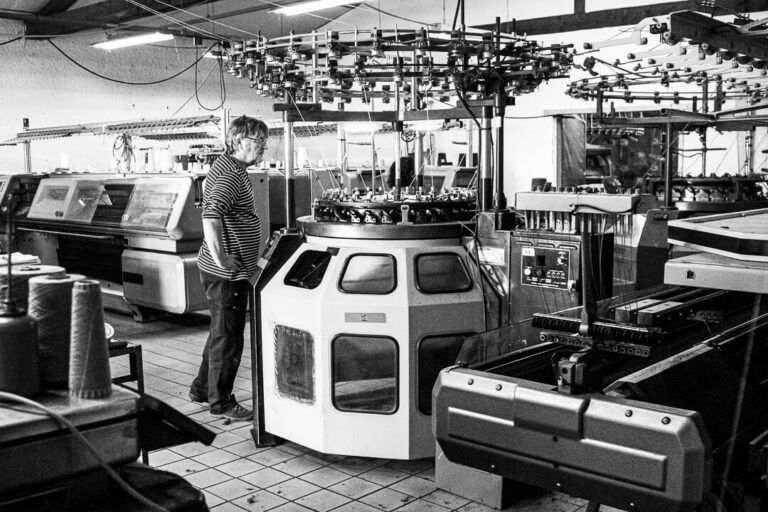 Technicien contrôlant une tricoteuse circulaire dans un atelier de tricotage de laine à Charlieu (Loire).