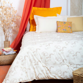 Lit en laine avec couette et oreillers dans une chambre à l’ambiance bohème.