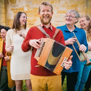 Sept personnes souriantes portant des vêtements en laine Ardelaine, fabriqués en France.